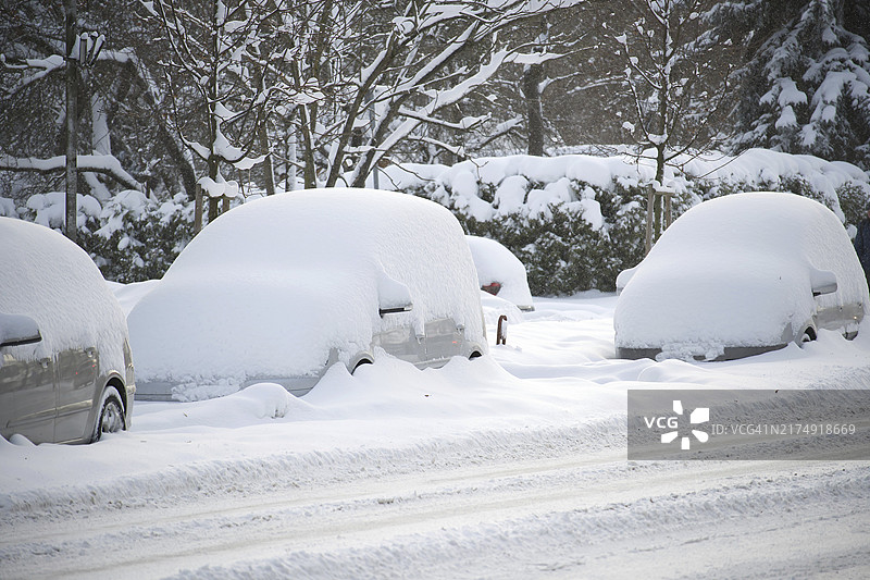 多辆汽车被厚厚的积雪覆盖的冬季景象，一些汽车几乎完全被雪掩埋图片素材