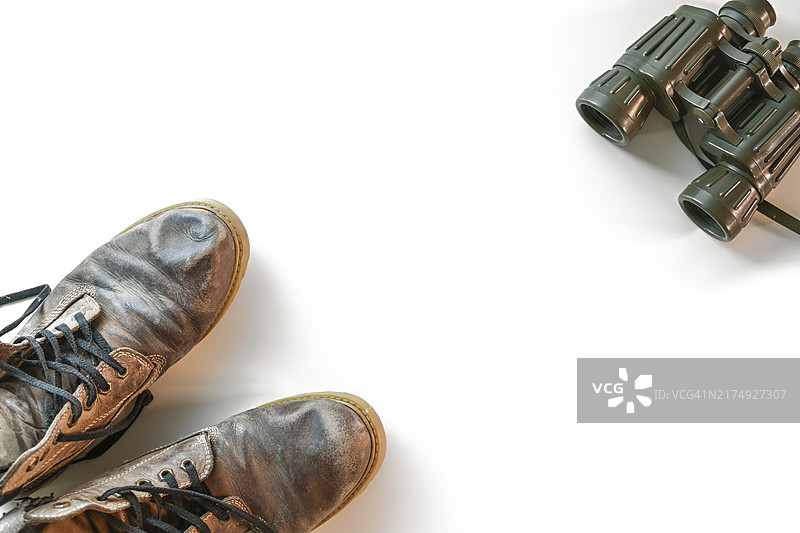 白色背景上的旧徒步靴和双筒望远镜，徒步旅行概念图片素材