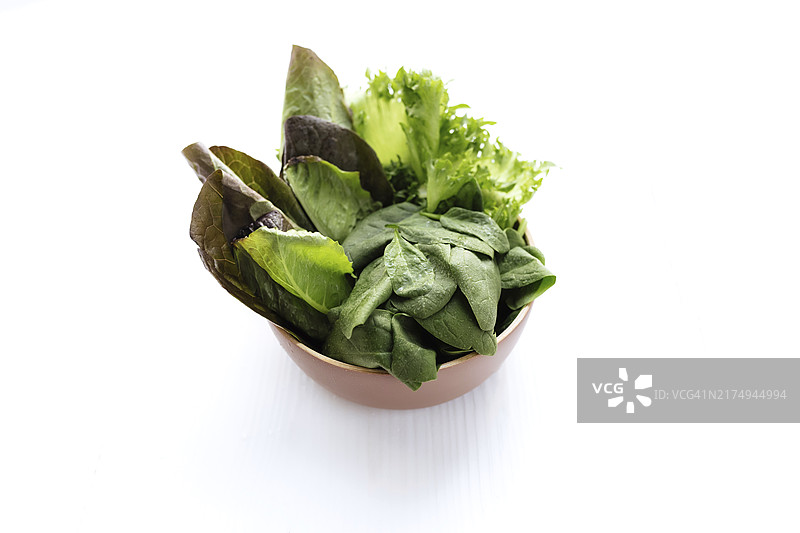 菠菜、生菜、罗马生菜和罗勒的绿色沙拉叶碗俯视图：健康素食概念图片素材