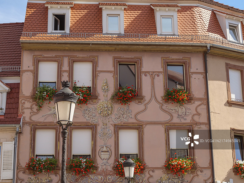 用鲜花装饰的窗户和房屋的精致外墙装饰，位于法国阿尔萨斯魏森堡的街道旁图片素材