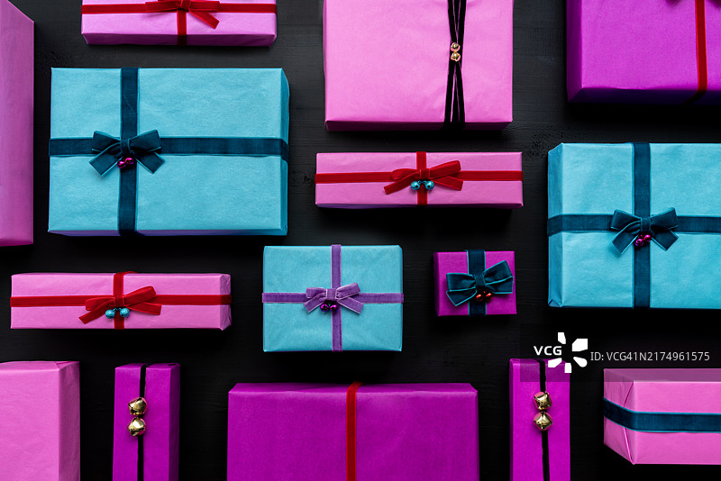 黑色背景上排列的各种尺寸的彩色包装礼物，为特别的庆祝场合准备图片素材