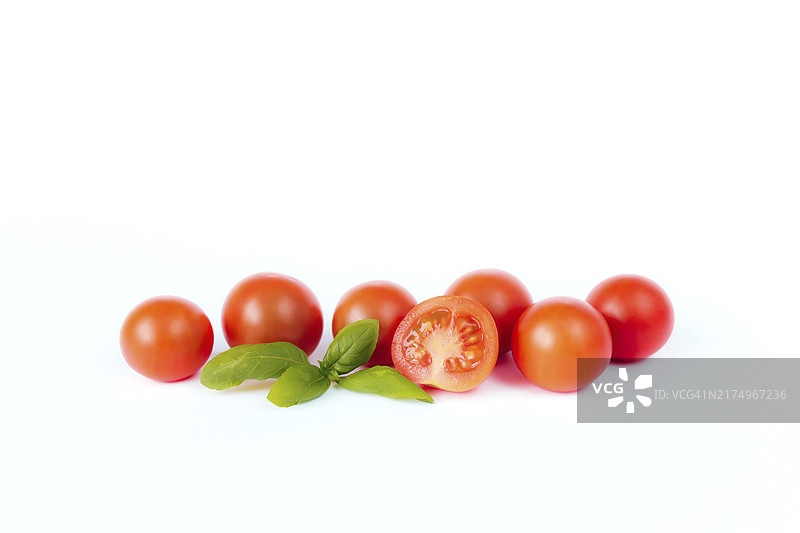 白色背景上的红色小番茄和绿色罗勒图片素材