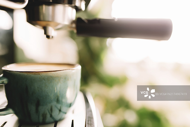 咖啡机旁的绿色咖啡杯，咖啡时间，虚化背景图片素材