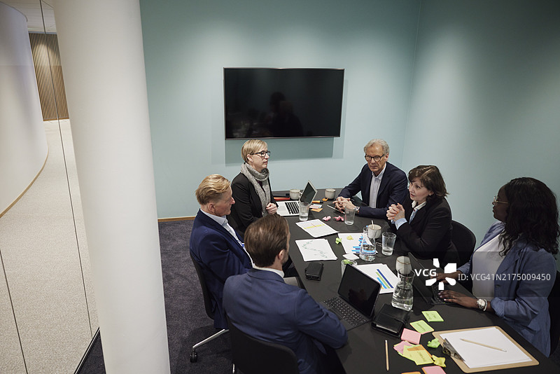 公司同事在办公室会议桌上讨论新策略图片素材