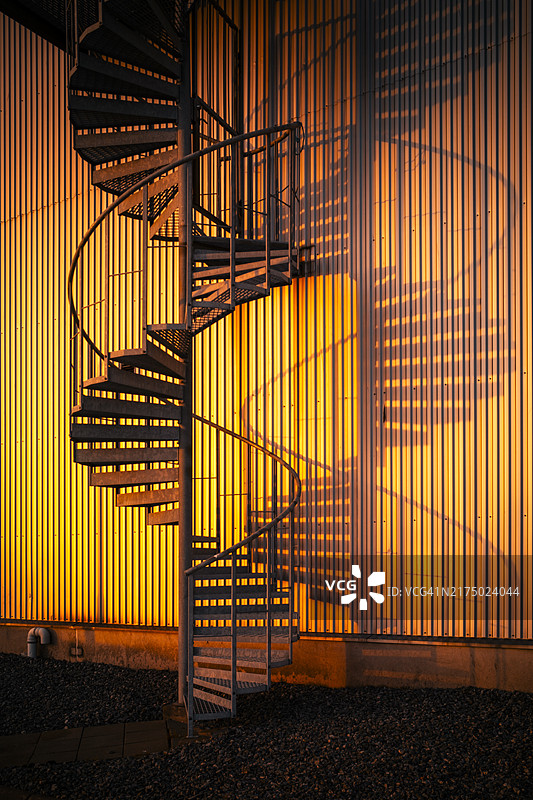日落时分的靠墙螺旋楼梯图片素材