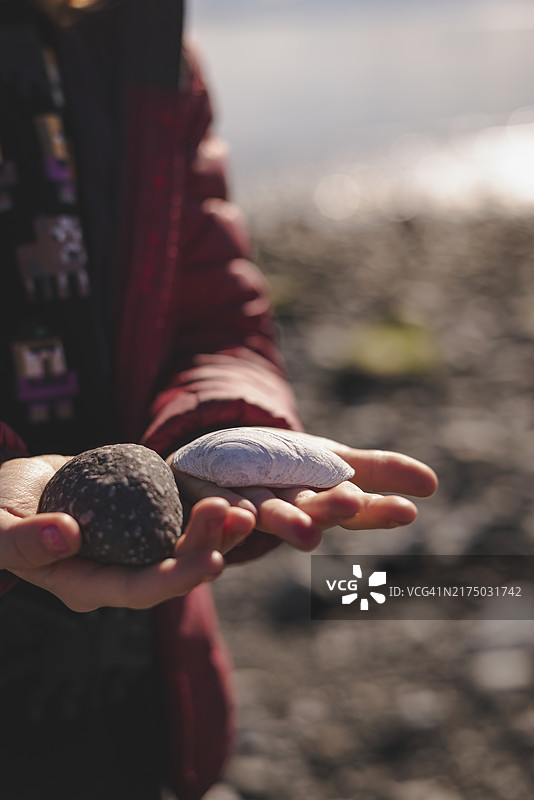 阳光明媚的日子里，女孩拿着石头的中段照片图片素材