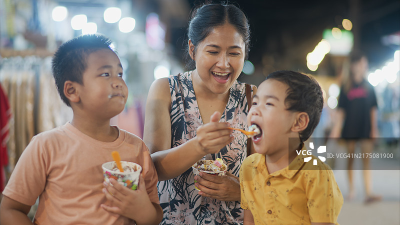在当地街头市场，母亲和两个儿子一起享用冰淇淋图片素材