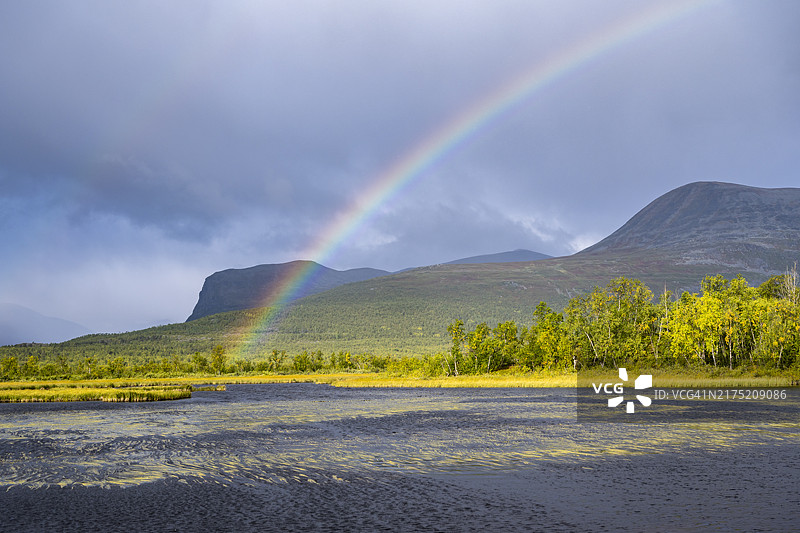 瑞典拉普兰尼卡洛克塔Visttasjohka河三角洲雷雨中的彩虹图片素材
