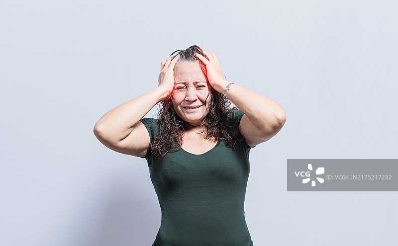 头痛的女人在孤立的背景下，头痛的概念，女人给自己头部按摩，偏头痛的概念图片素材