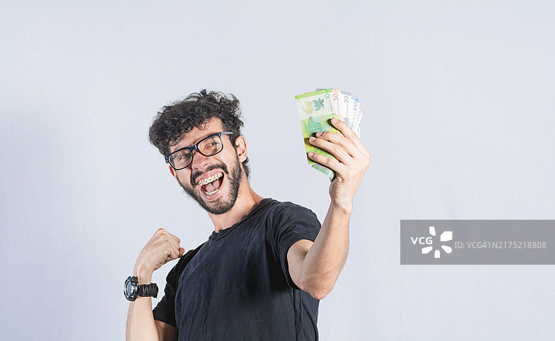 手持钞票的兴奋男人，快乐男人手持纸币，收入和储蓄概念图片素材