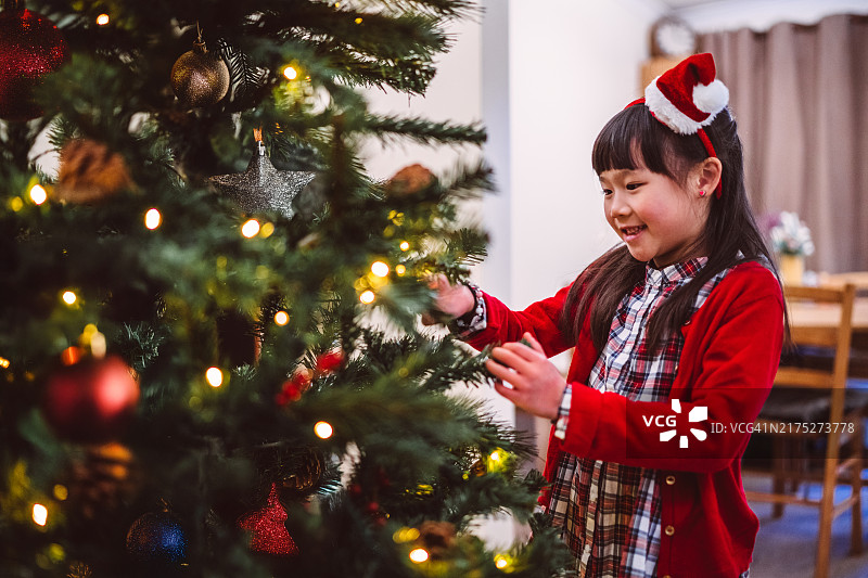 笑容满面的年轻女孩在家里装饰圣诞树，欢度节日图片素材