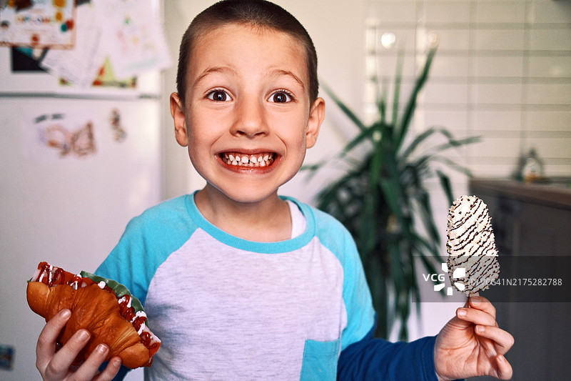 一手拿着冰淇淋、一手拿着三明治的可爱小男孩图片素材
