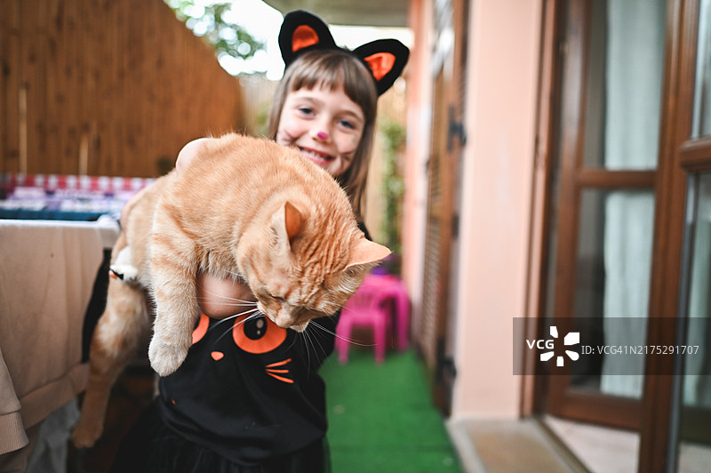 快乐女孩与姜黄色猫的正面肖像图片素材