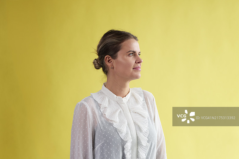 站在黄色背景下的年轻女商人图片素材