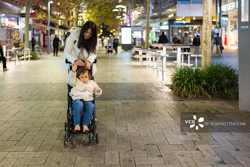 年轻亚洲女人和孩子在精品店外看橱窗图片素材