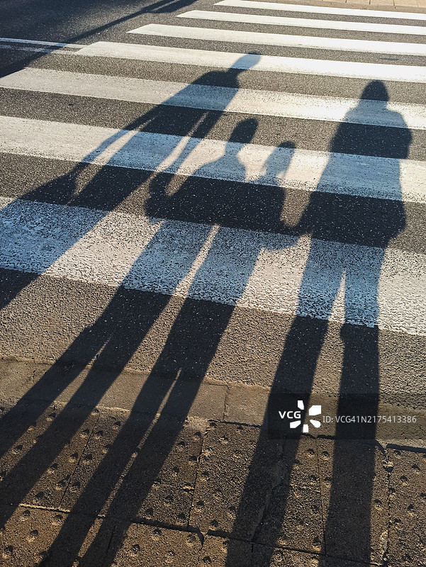 人行横道上，一家人手牵手的影子图片素材