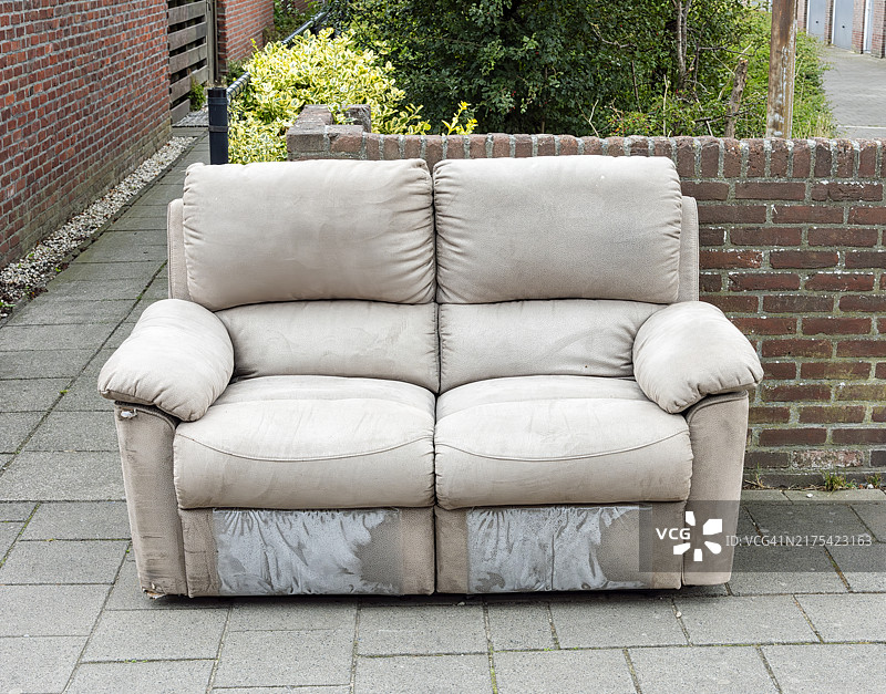 被丢弃在人行道上的破旧双人沙发图片素材