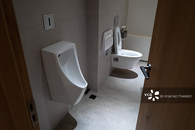 从门外看：厕所里的小便池和洗手盆图片素材