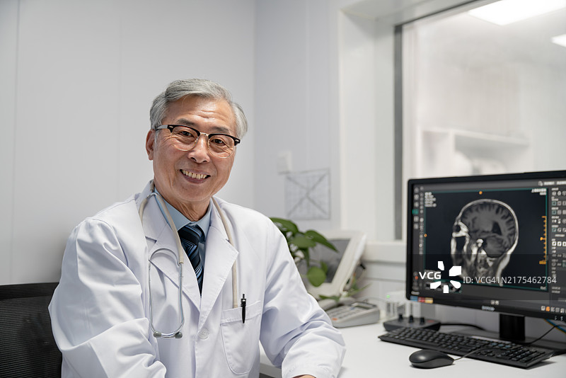 医院控制室里的老年男医生肖像。背景是病人脑部扫描MRI图像图片素材