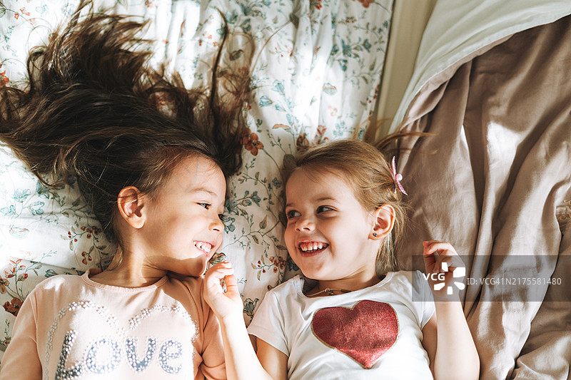 两个小女孩朋友在家聊天，躺在床上图片素材