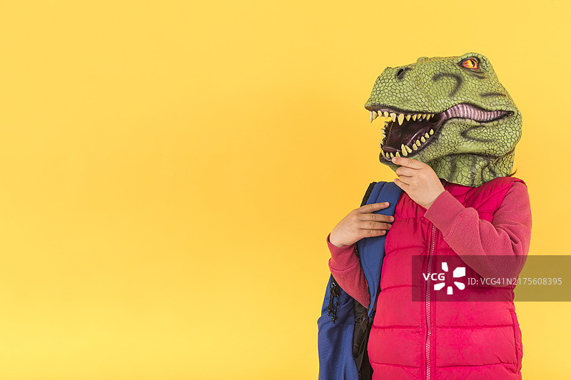 戴恐龙面具穿粉色背心的人在黄色背景前图片素材