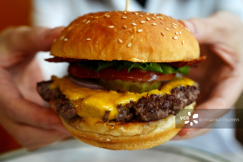 女人手持牛肉芝士汉堡图片素材