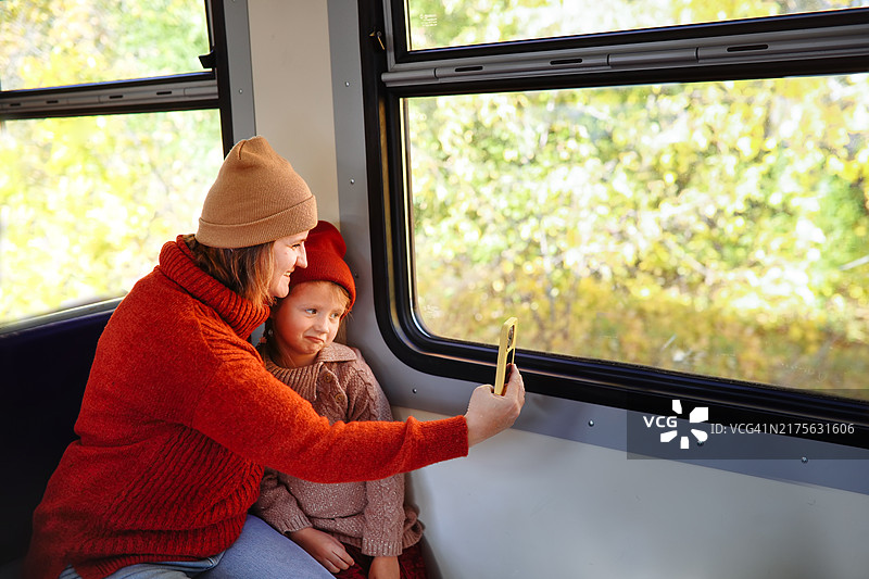 胖妈妈在火车上用智能手机与孩子自拍，宣传安全带孩子旅行。图片素材