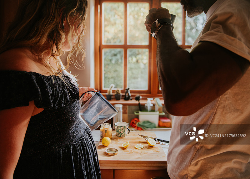 孕妇在厨房里和伴侣一起倒水图片素材