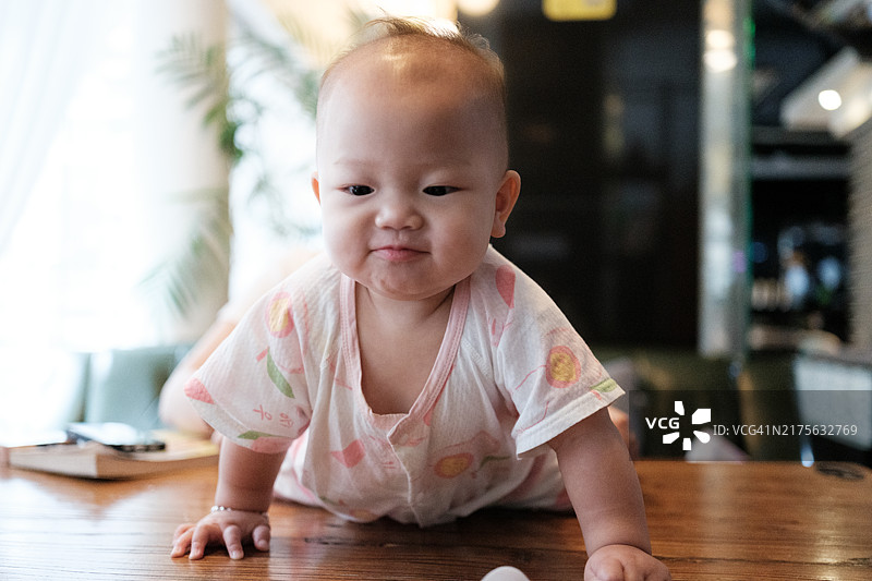 在桌子上爬行的可爱亚洲女婴图片素材