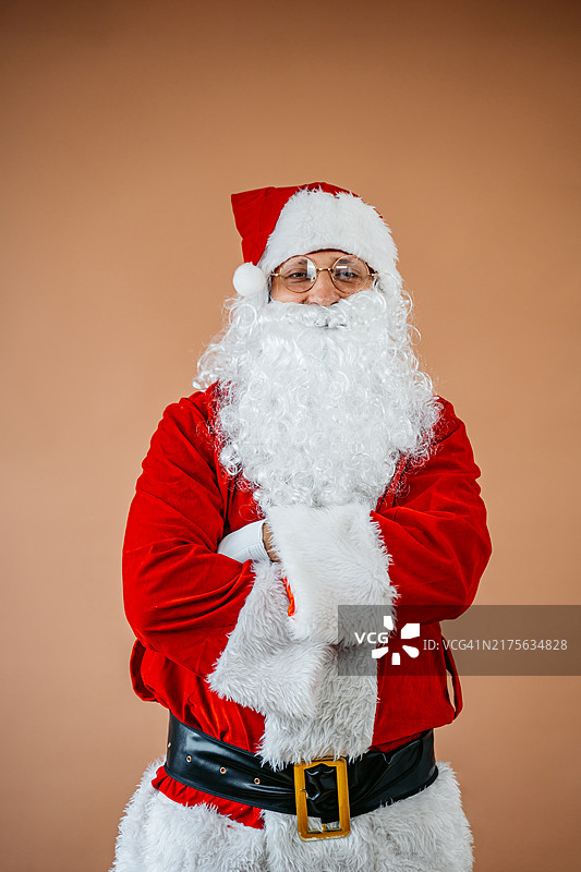 米色背景下双臂交叉的圣诞老人图片素材