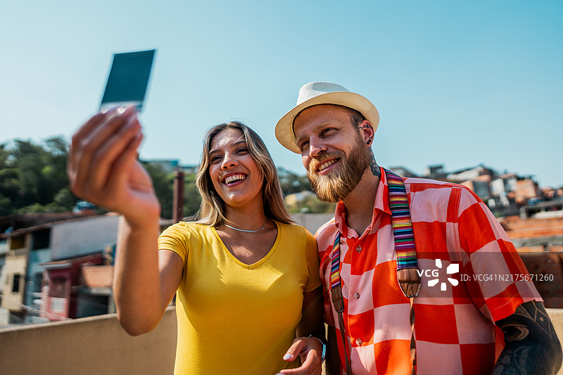 一对情侣在巴西贫民窟的阳台上查看冲洗好的照片图片素材