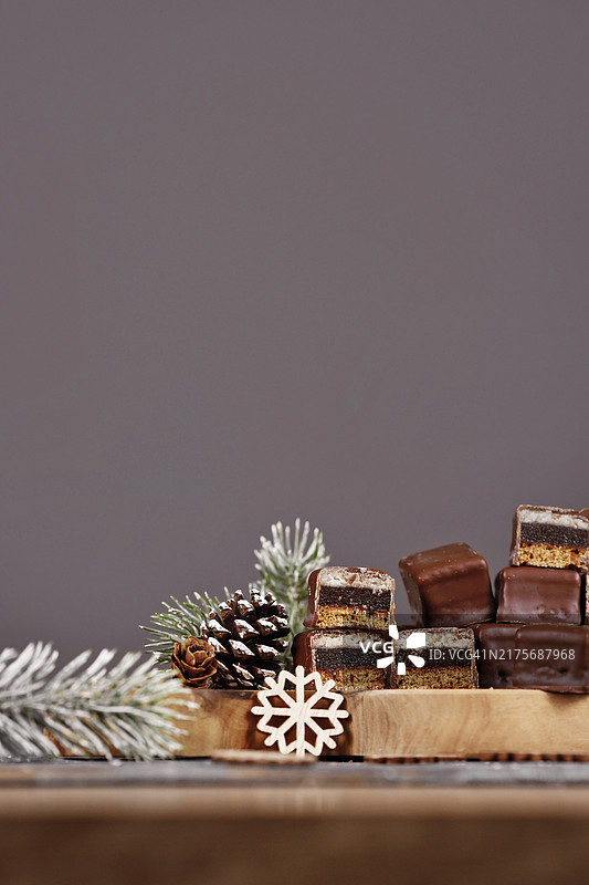 半个传统德国甜点“Dominosteine”，由姜饼、果冻和杏仁糖层组成，外层裹着巧克力糖衣，深灰色背景图片素材