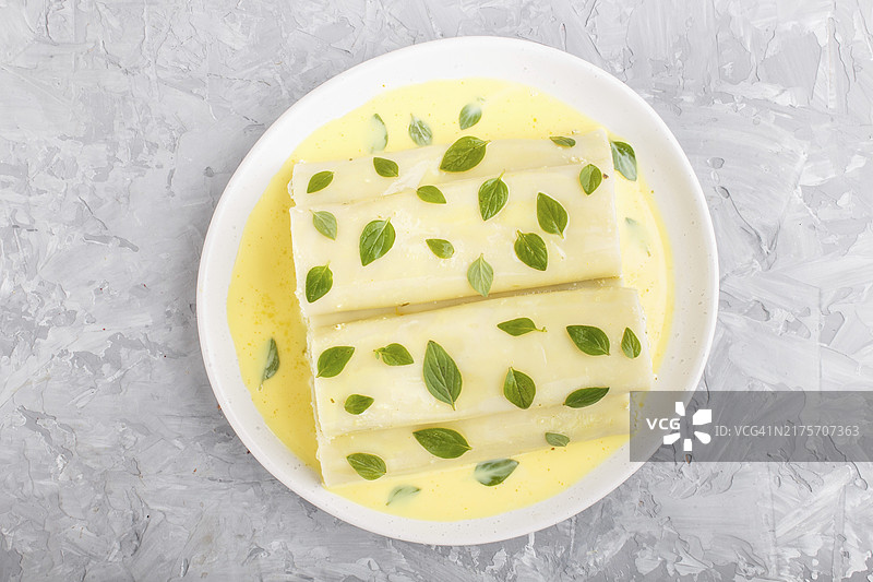 灰色混凝土背景上的鸡蛋酱、奶油干酪和牛至叶意大利卷面，俯视图，平铺，特写图片素材