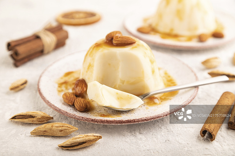 灰色水泥背景上的焦糖酱白色牛奶冻，侧视特写图片素材