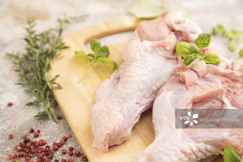 木制砧板上配香草和香料的生火鸡翅，棕色水泥背景，侧视图，特写，选择性聚焦图片素材