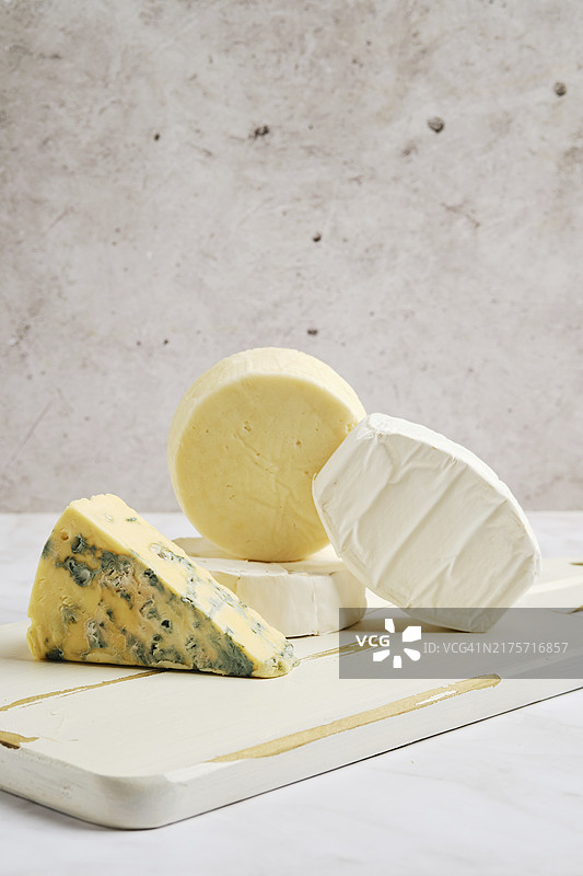 木制砧板上的布里奶酪、卡门贝尔奶酪、山羊奶酪和蓝纹奶酪图片素材