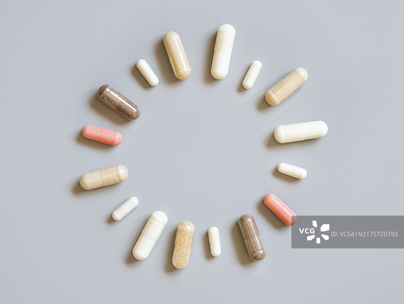 灰色背景上的圆形胶囊混合物，服用膳食补充剂图片素材