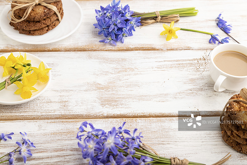 燕麦饼干、雪滴花、风信子、水仙花和咖啡杯组成的边框构图，白色木质背景。侧视图，留白，静物。早餐、早晨、春天概念图片素材