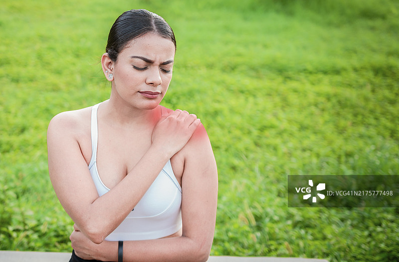 坐在户外的年轻女子肩膀疼痛图片素材