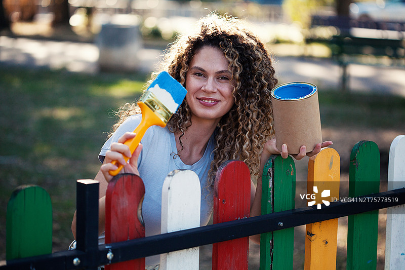 年轻女人粉刷木栅栏图片素材