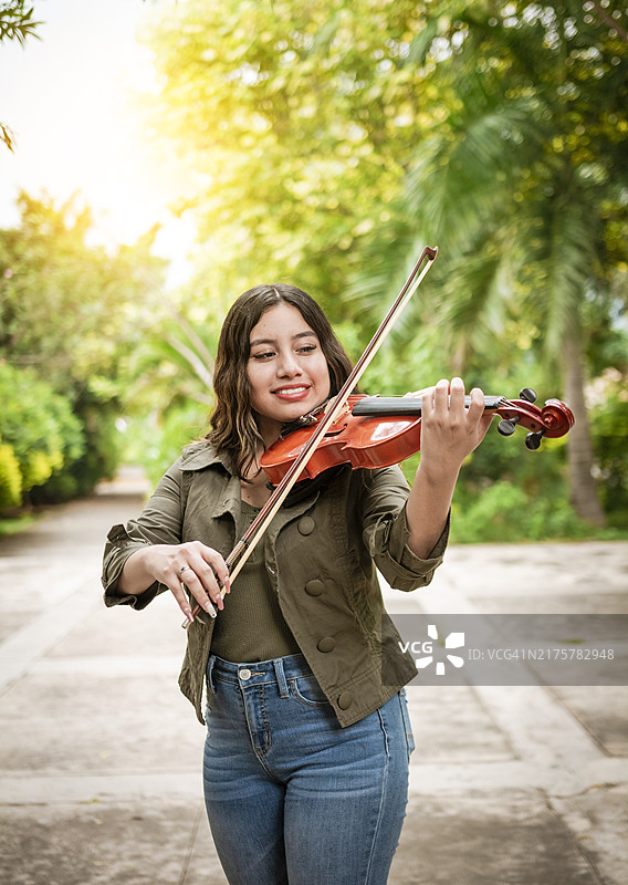 户外拉小提琴的女孩肖像：微笑的女小提琴手图片素材