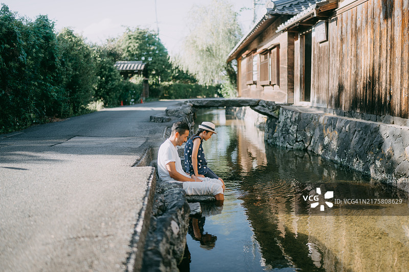 父亲和小女儿在古老的日本城镇的运河旁放松。图片素材