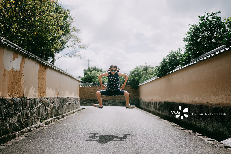年轻女孩在日本山口县萩市的历史街道上跳跃图片素材
