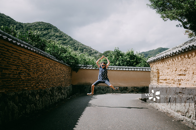 年轻女孩在日本山口县萩市的历史街道上跳跃图片素材