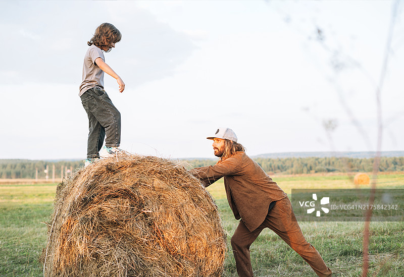 日落时分父子在草垛旁玩耍图片素材