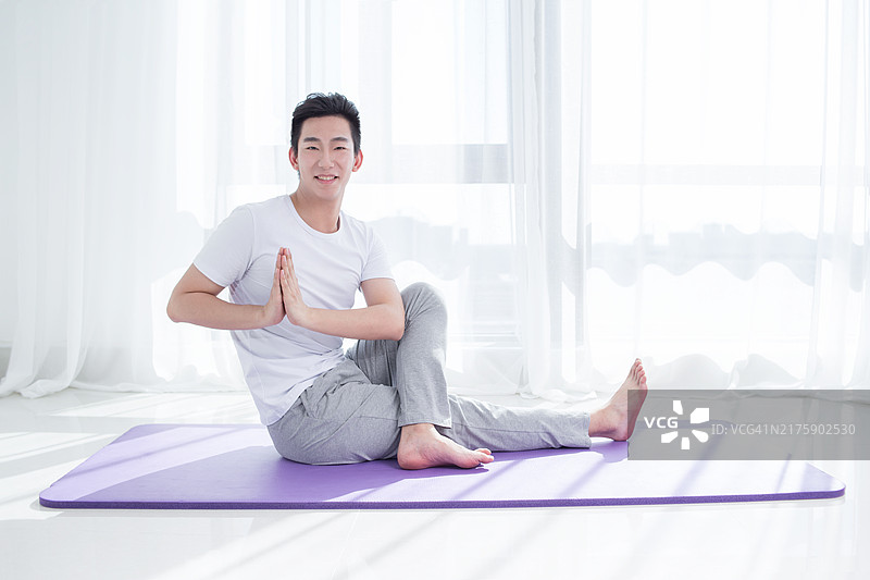 年轻男人在房间里做瑜伽图片素材