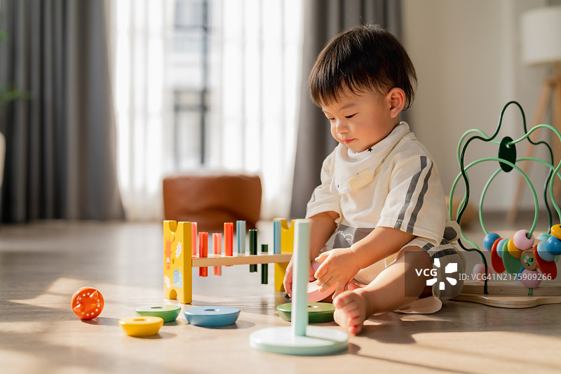 快乐的亚洲小男孩（12-17个月）坐在客厅里玩耍图片素材
