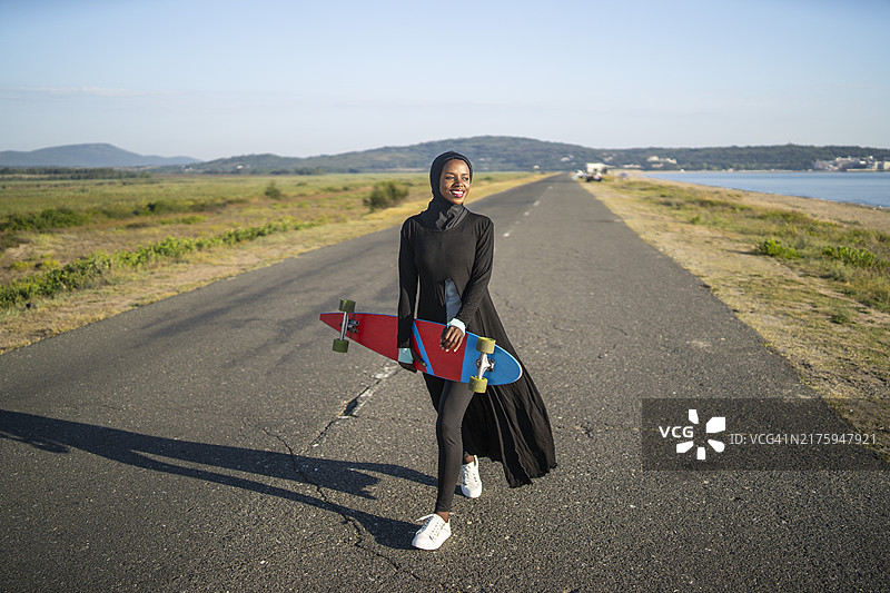 在笔直的道路上的运动女性滑板运动员图片素材