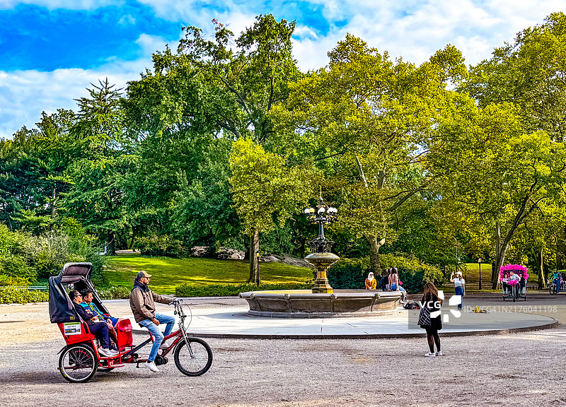 在纽约市樱桃山喷泉附近的人力三轮车上的人们图片素材