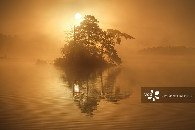 秋季湖畔岛屿的阳光与晨雾图片素材